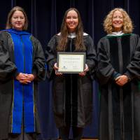 Awardee posing after receiving award, with Provost and Christine